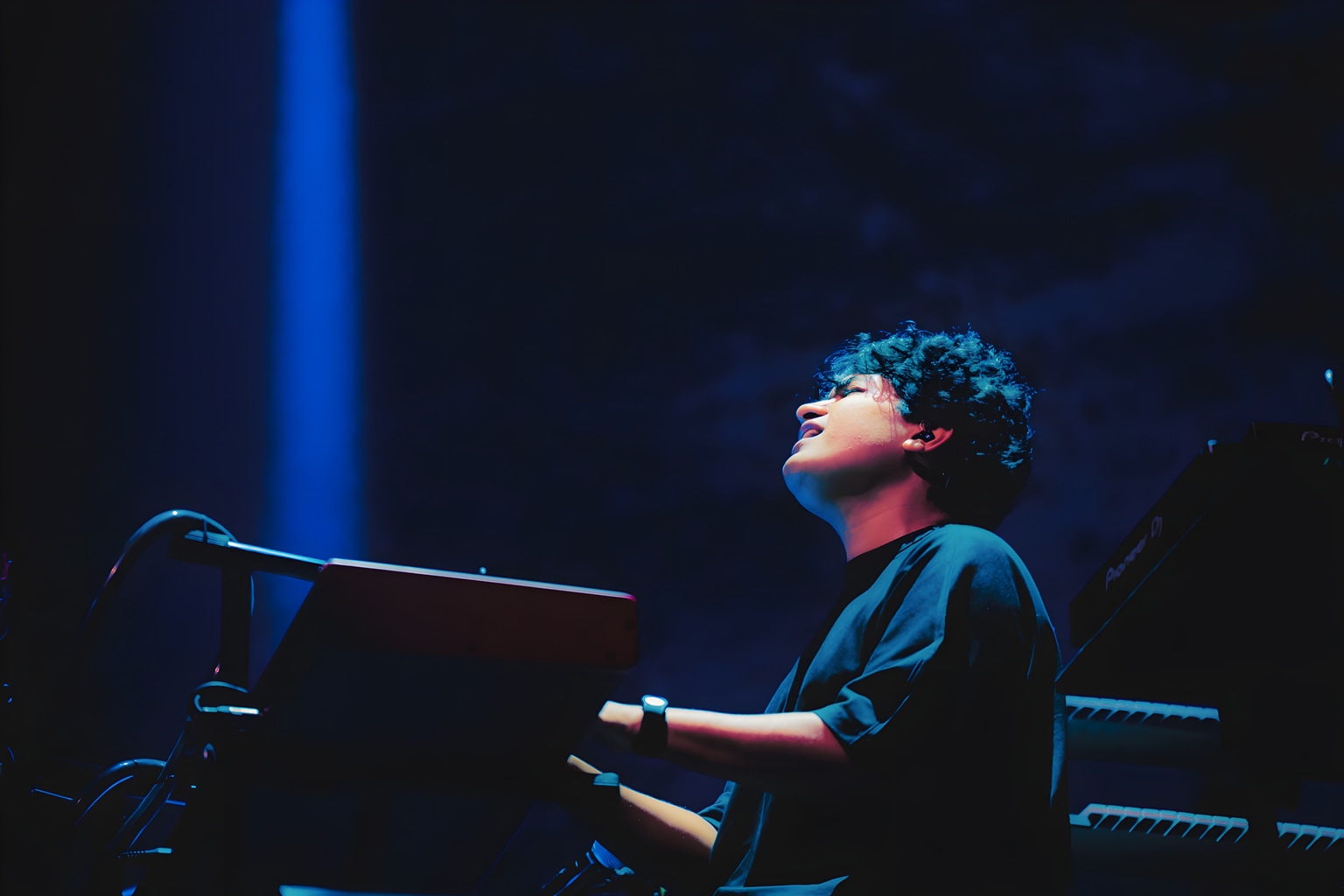 Shashwat Sachdev at the keyboards beneath blue stage light.